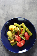 Roasted asparagus and tasty colorful pasta with vegetables on plate on colorful background