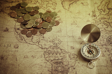 Vintage compass and coins on old map