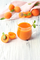 Cup of apricot juice and fresh fruits on table close up