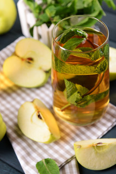 Glass of apple juice with fruits and fresh mint on table close up