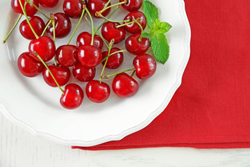 Sweet cherries on plate, on light background