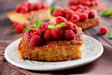 Fresh pie with raspberry in white saucer on wooden table, closeup