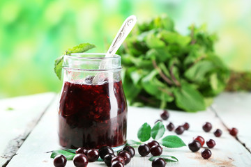 Jar of gooseberry jam on wooden table on natural background
