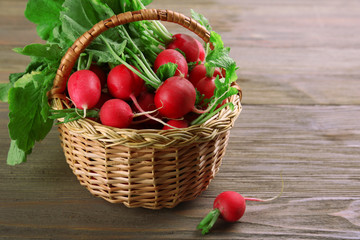 Fresh radishes in basket on wooden background