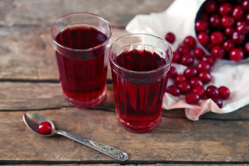Two glasses with cherry juice on table, on wooden background