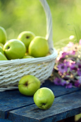 Green apples with bouquet of wildflowers on wooden table, closeup
