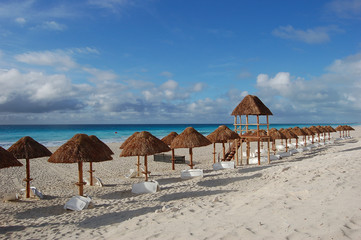 White sand beach with thatched cabanas and blue waters