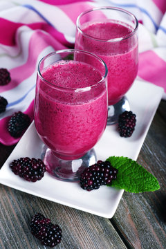 Glasses of blackberry smoothie on wooden table, closeup
