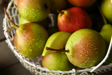 Ripe tasty pears in basket on table close up