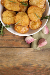 Delicious baked potato with rosemary in bowl on table close up