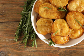 Delicious baked potato with rosemary in bowl on table close up