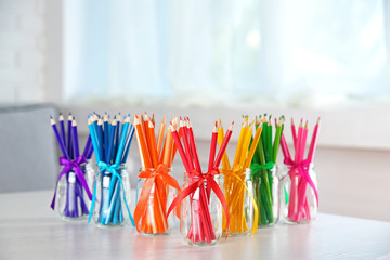 Bright pencils in glass jars on table