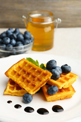 Sweet homemade waffles with forest berries and chocolate sauce on table background