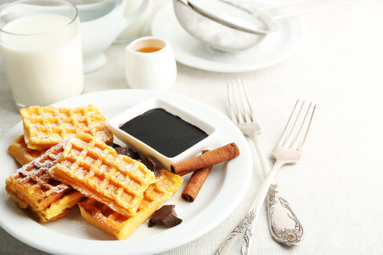 Sweet homemade waffles on plate, on light background