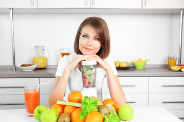 Young beautiful woman using blender, preparing orange juice