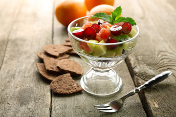 Fruit salad in glass bowl, on wooden background
