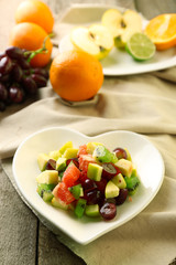 Fruit salad on plate, on wooden background