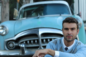 A young handsome man and a classic car in the background 