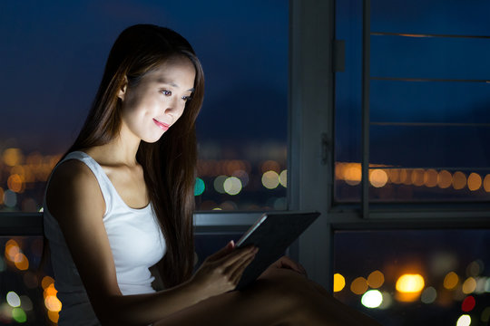 Woman using tablet pc at night
