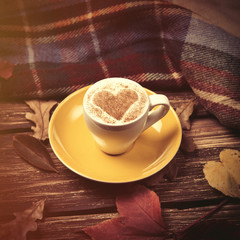 Autumn leafs, scarf and coffee cup on wooden table.