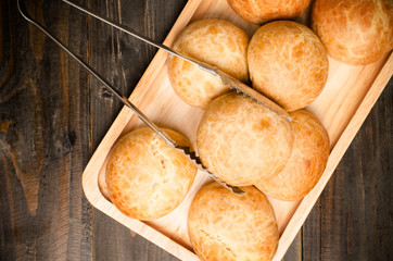 Homemade buns with tong on wooden plate