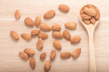 Almonds in spoon, on the wooden