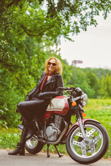 Fototapeta na wymiar Biker girl in leather jacket on a motorcycle. Warm toned image