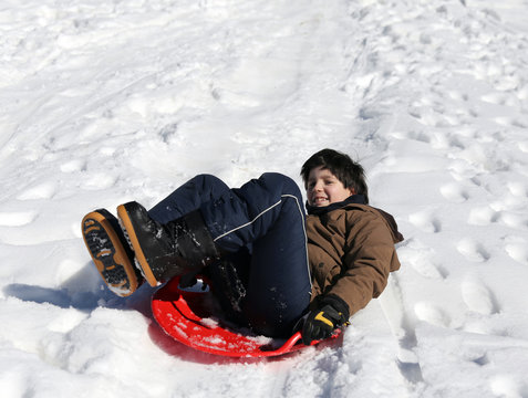 Boy plays with sledging in winter on the white snow