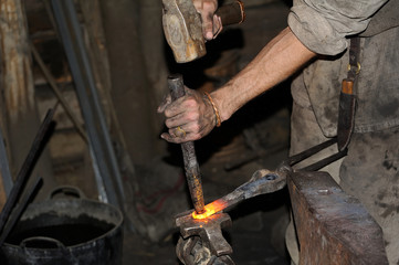 Blacksmith working on metal on anvil at forge high speed
