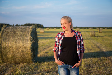 Naklejka na ściany i meble beautiful romantic country girl walking in field with haystacks