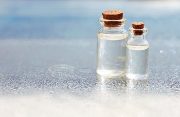 bottles transparent liquid fluid water surface blue light tranquil spa empty background soft focus