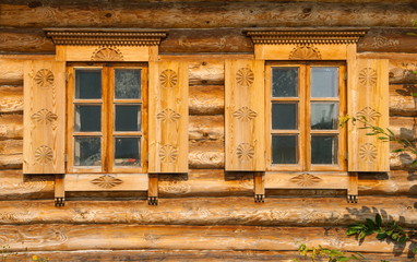 Windows with shutters with wood carving on the wall of the log house