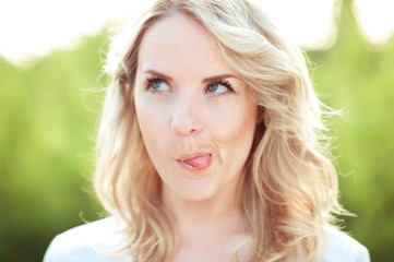 Fototapeta premium Young blonde girl making faces outdoors. Looking up. Having fun. 