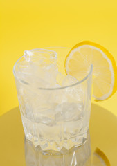 Drink with Ice and Lemon Slice on Yellow Background