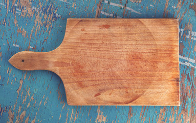 Cutting board on rustic wooden kitchen table, top view