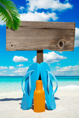 Flips Flops stehen vor leerem Holzschild am Strand