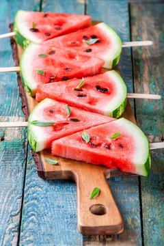 Slices of fresh juicy watermelon on a cutting board with mint