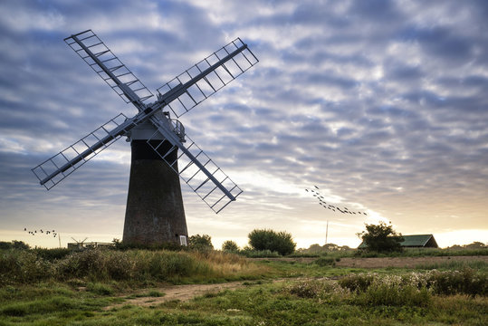 Old pump windmill in English countryside landscape early morning