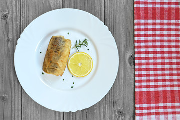 A piece of fried hake fish on the plate