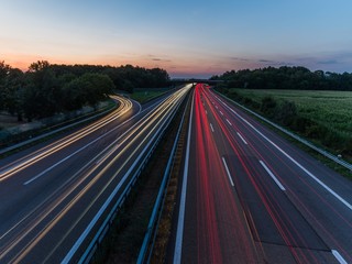 german highway at sunset with light trails from passing cars