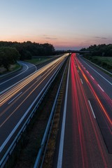 german highway at sunset with light trails from passing cars - 89218890