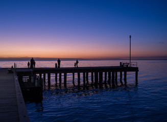 Fototapeta na wymiar Silhouettes of people standing on a pier at sunset