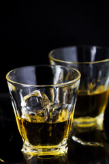 Two glasses of whiskey with ice cubes