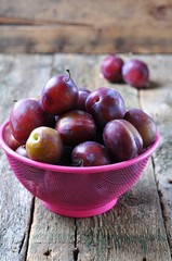 Fresh organic plums in a basket on a wooden table