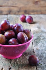 Fresh organic plums in a basket on a wooden table