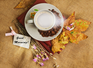 The cup of coffee lying on the books with maple leaves