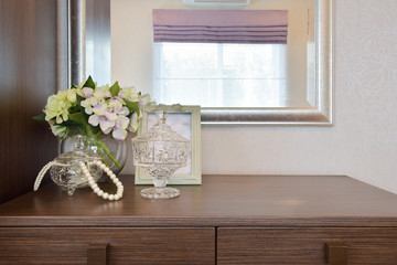 Jewery crystal jar with picture frame and flowers on the wooden
