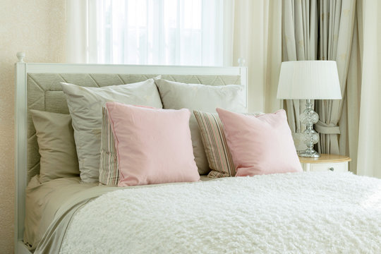 luxury bedroom interior with pink pillows and reading lamp on be