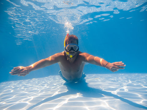 Full Length Of A Young Man Wearing Snorkel Underwater