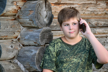 teenager boy talking on cell phone standing by  wooden wall